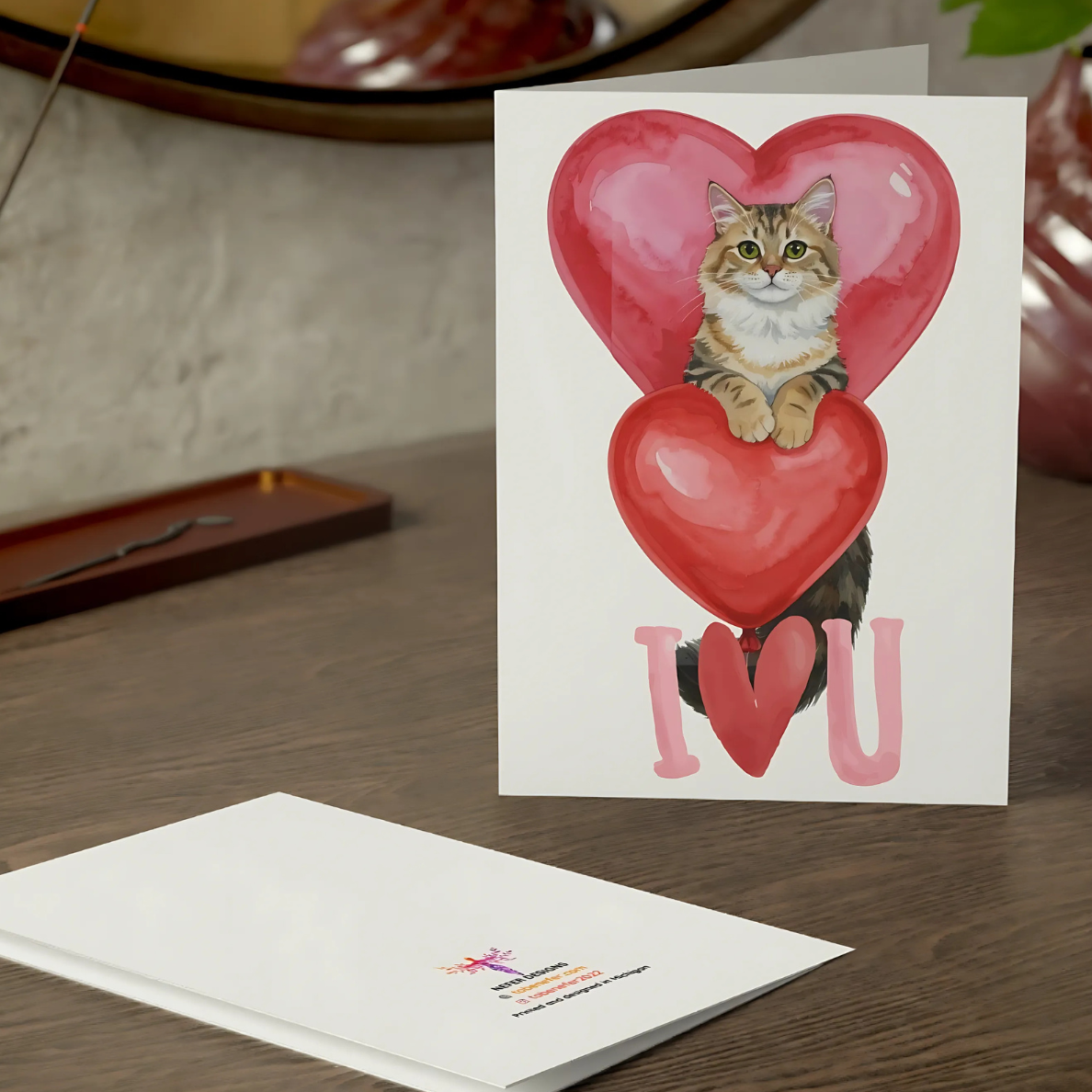 Greeting card with a cat illustration and 'I love you' text on a wooden surface.