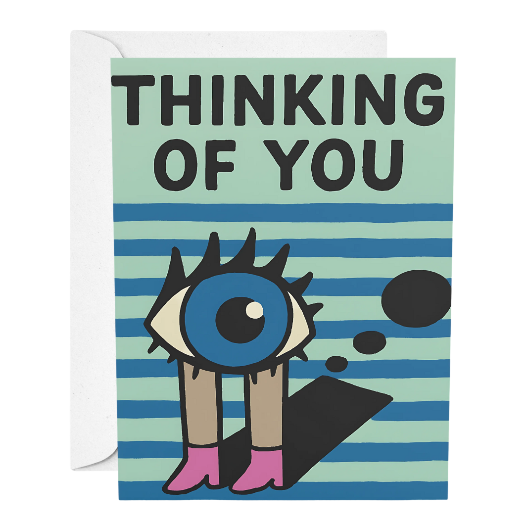 Greeting card with 'Thinking of You' text and a stylized eye design on a striped background.