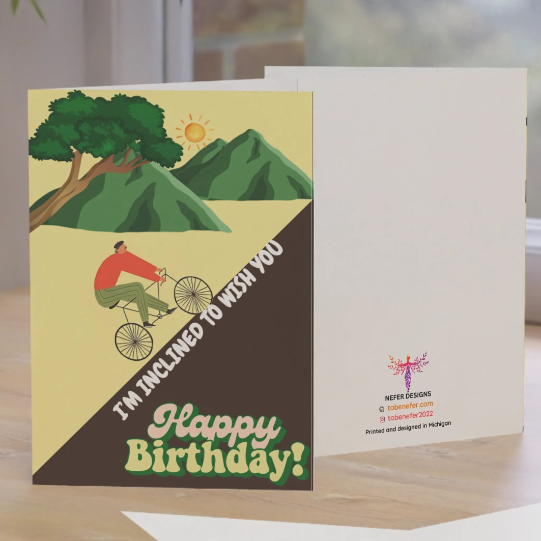 Birthday card with a cyclist and mountains design on a wooden surface