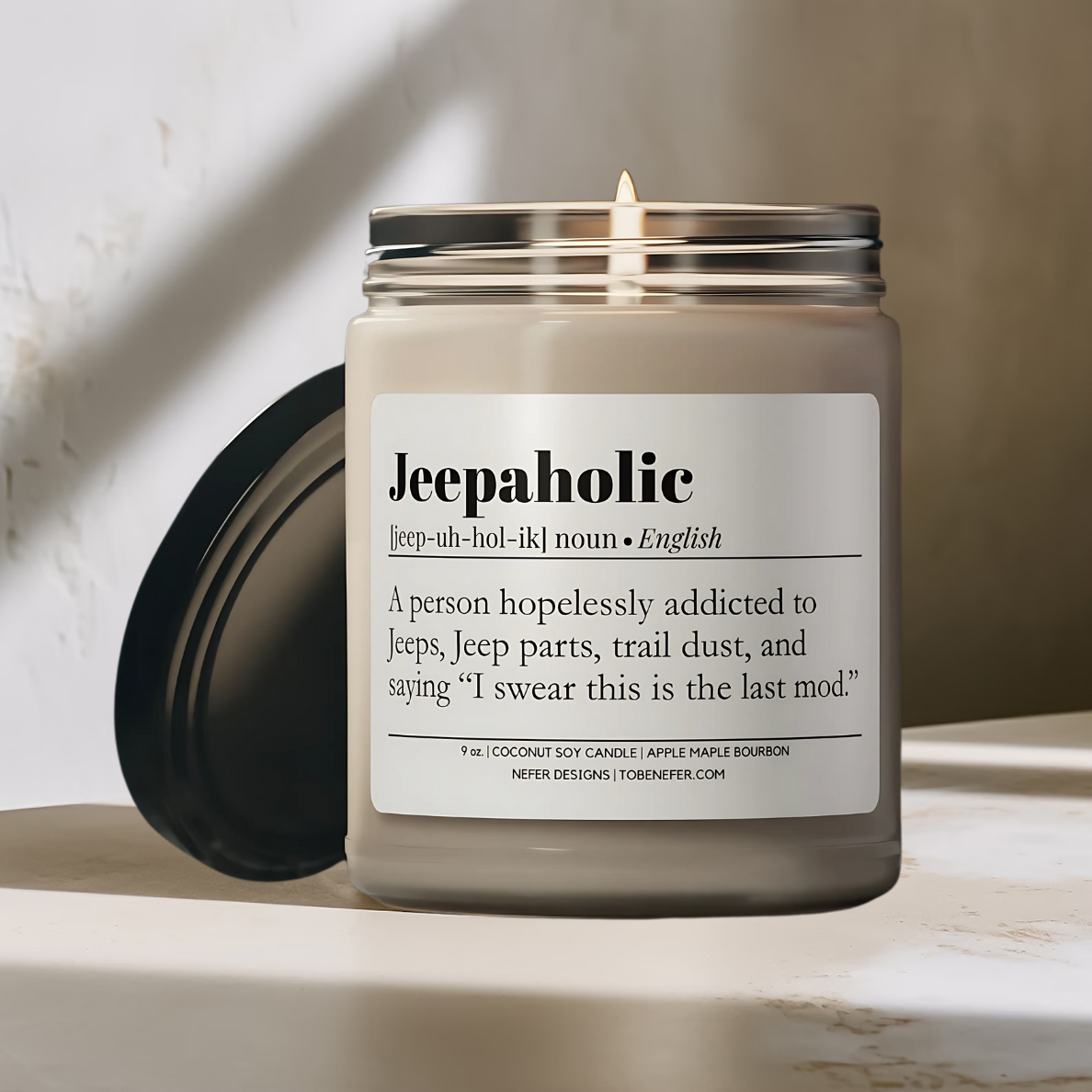 Burning Jeepaholic candle in a minimalist amber glass jar with a clean cotton wick, sitting on a marble surface.