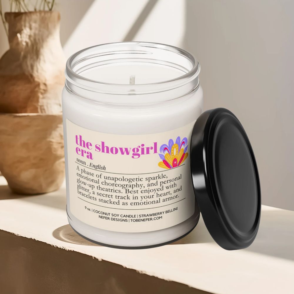 Candle in a jar with a label titled 'the showgirl era' on a shelf.