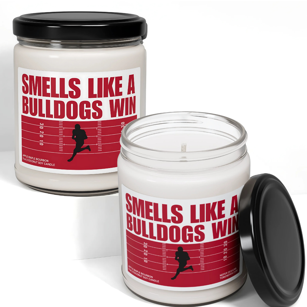 A Georgia Bulldogs-themed soy candle with a label that says 'Smells Like a Bulldogs Win | Lucky Game Day,' sitting on a marble surface