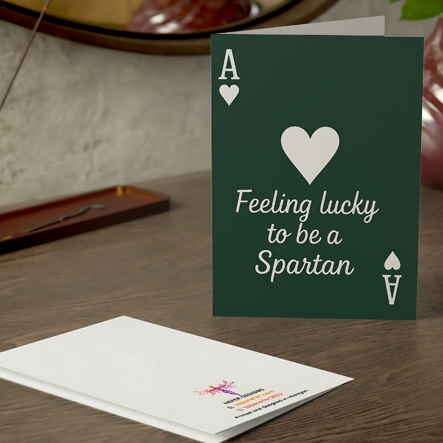 Greeting card with 'Feeling lucky to be a Spartan' text on a wooden surface