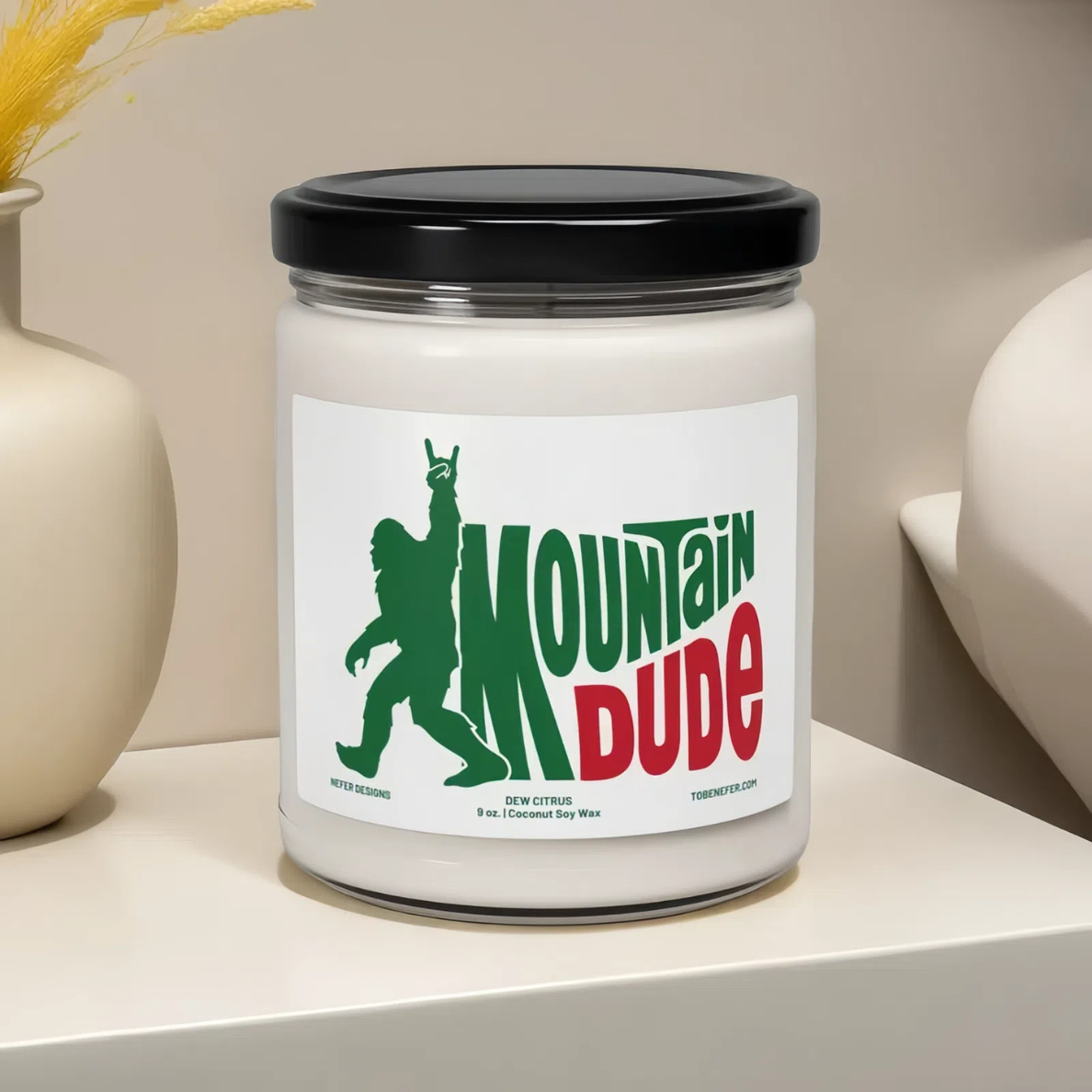A 9 oz Mountain Dude Soda Pop Soy Candle in a jar, featuring a vibrant bigfoot design with the wording of mountain dude. The candle is hand-poured with a coconut and soy wax blend, offering a refreshing lemon-lime soda scent. Perfect for soda lovers and nostalgia enthusiasts.