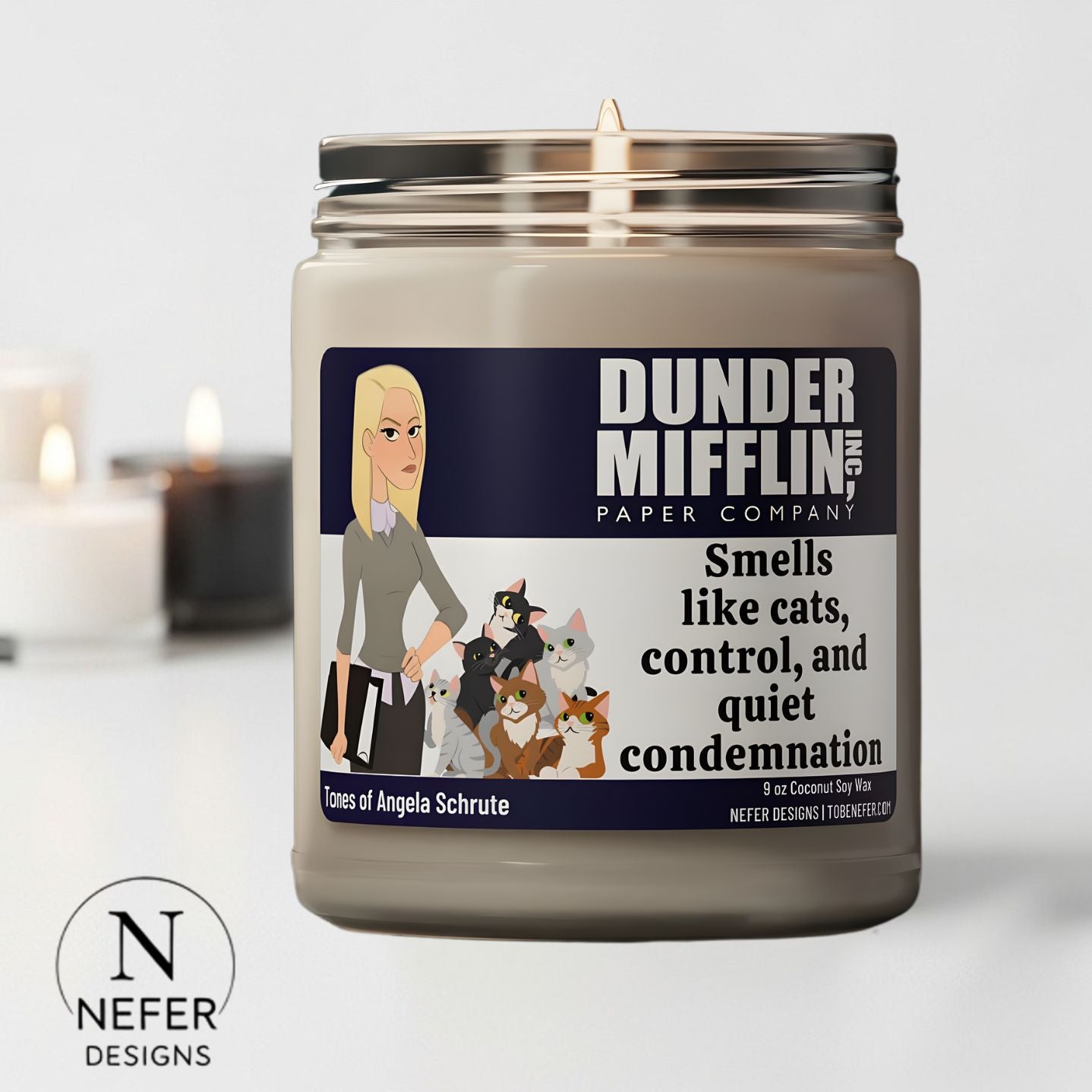 Candle with Dunder Mifflin label featuring Angela Schrute and cats, on a light background.