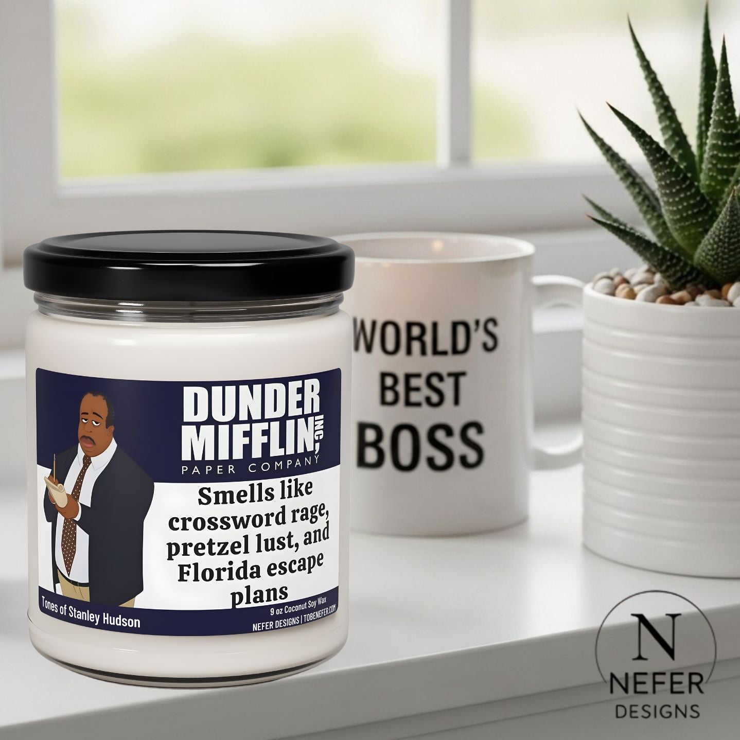 Candle with Dunder Mifflin label and 'World's Best Boss' mug on a surface.