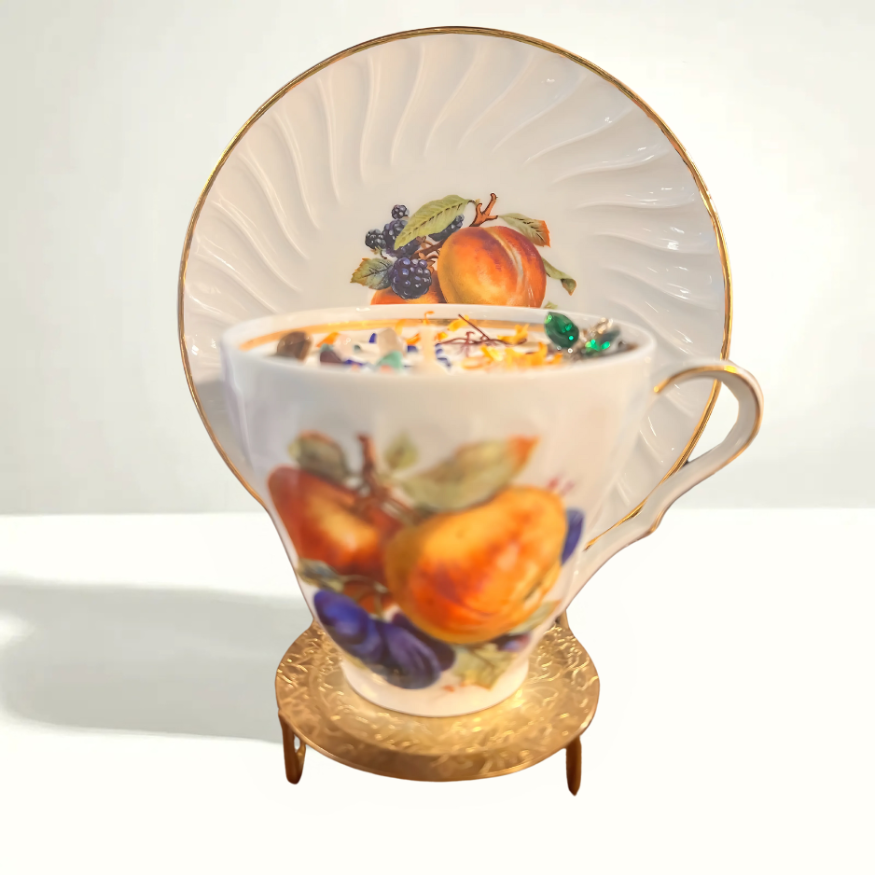 Charming vintage teacup and saucer featuring a colorful fruit motif with apples, grapes, and pears, highlighting traditional European porcelain design.