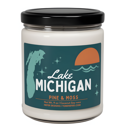 A candle labeled 'Lake Michigan' with the scent 'Pine & Moss.' The label states it is made of coconut soy wax, weighs 9 ounces.