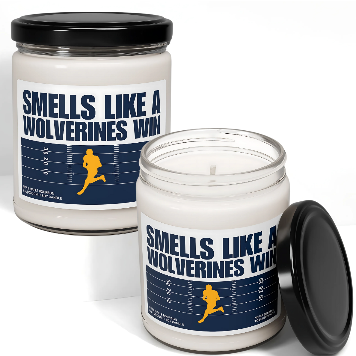 A Michigan Wolverines-themed soy candle with a label that says 'Smells Like a Wolverines Win | Lucky Game Day,' sitting on a wooden surface.