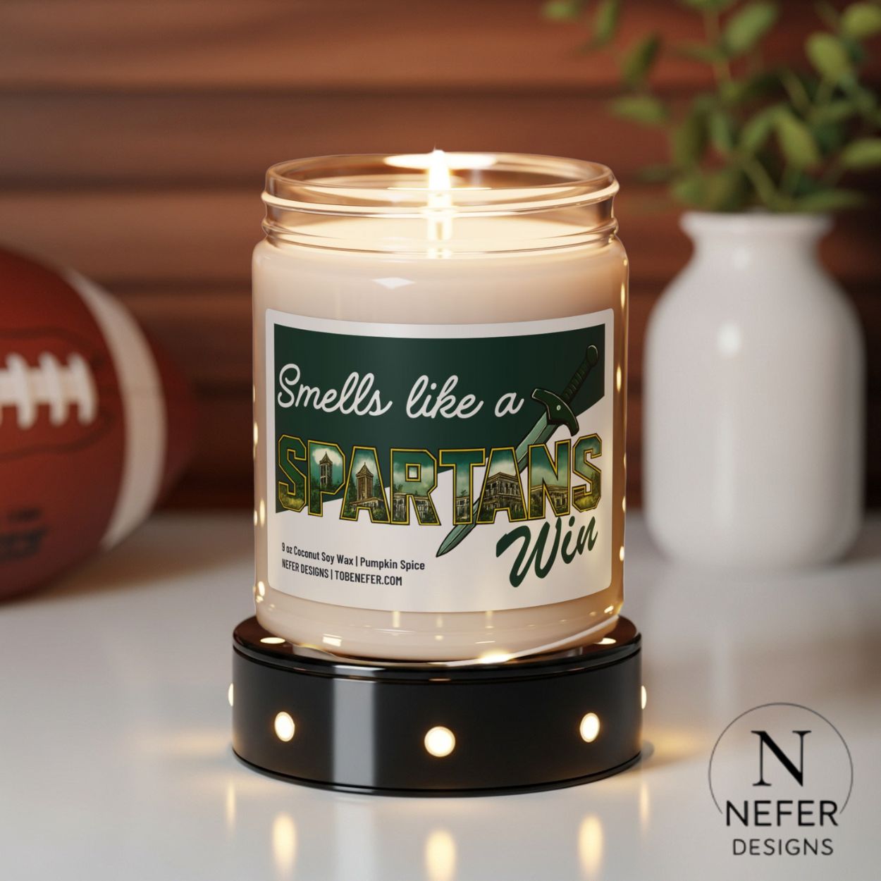 Candle in a jar with a label reading 'Smells like a Spartans Win' on a wooden surface.