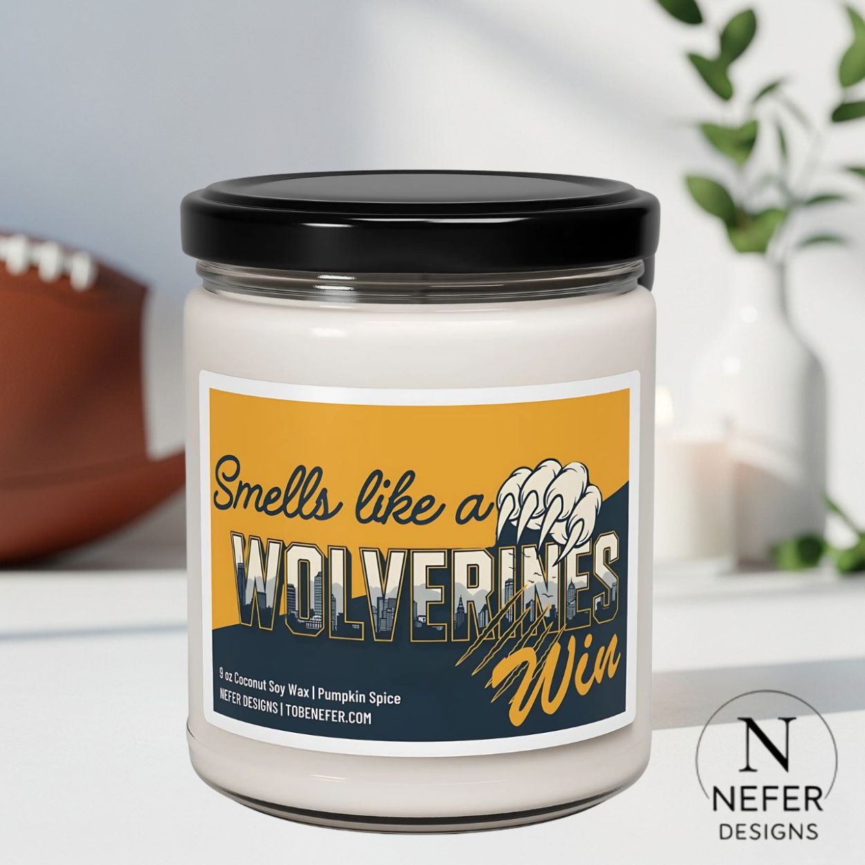 Candle jar with 'Smells like a Wolverines Win' label on a blurred background