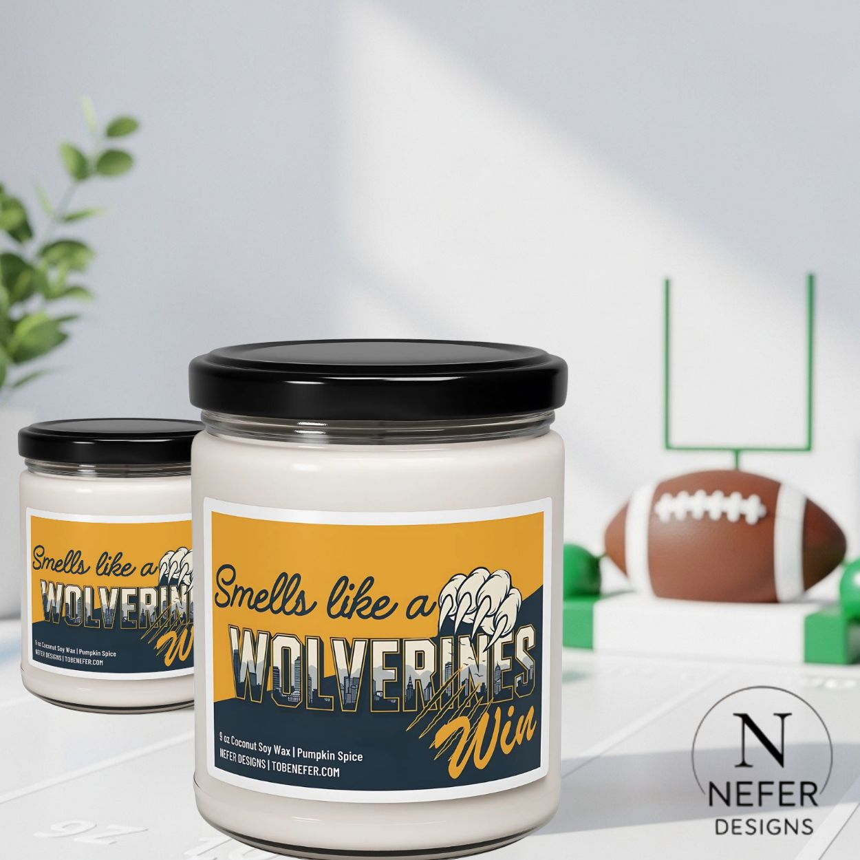 Two candles with 'Smells like a Wolverines Win' labels on a surface with sports-themed decor.