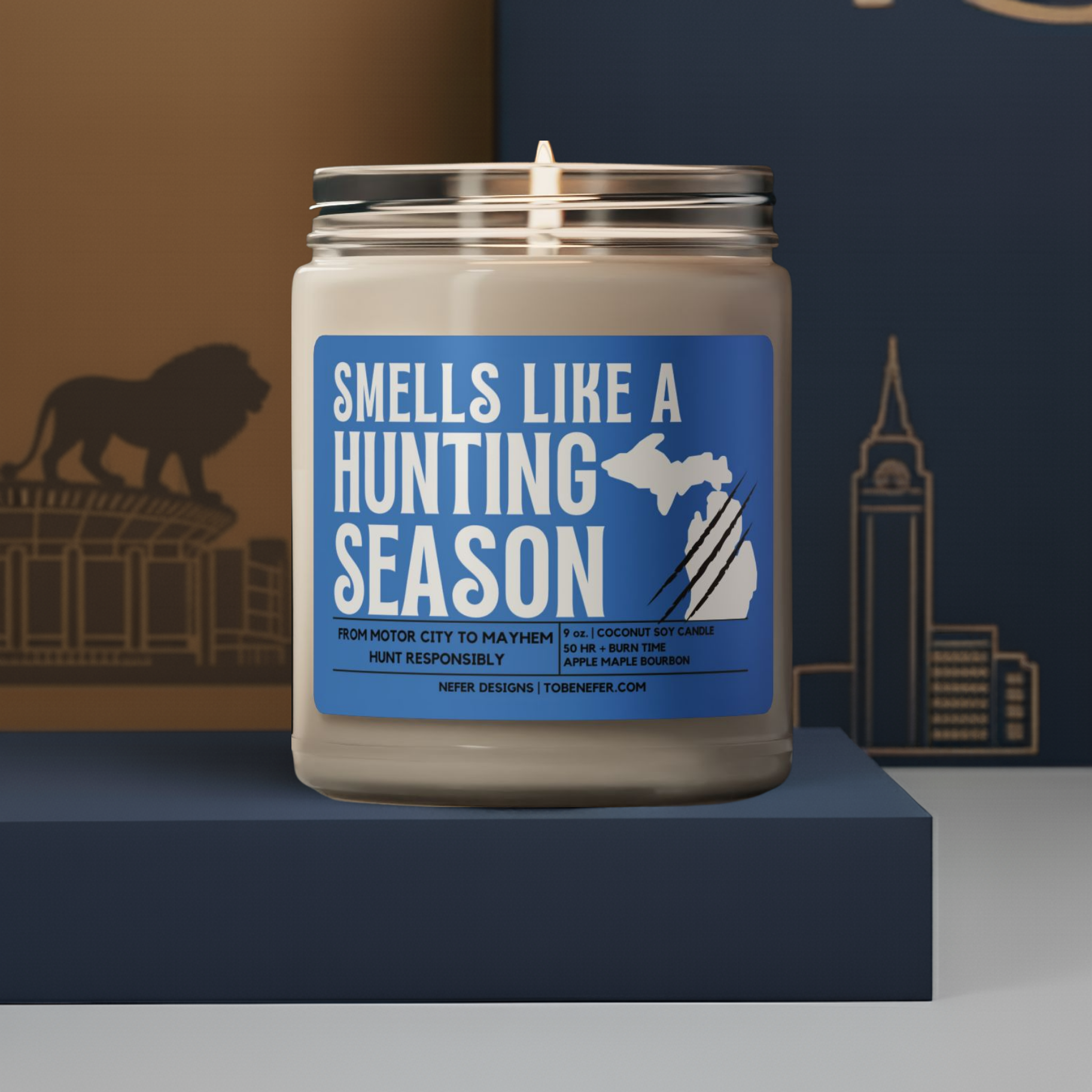 Candle in a jar with a blue label reading 'Smells Like a Hunting Season' on a dark blue platform.