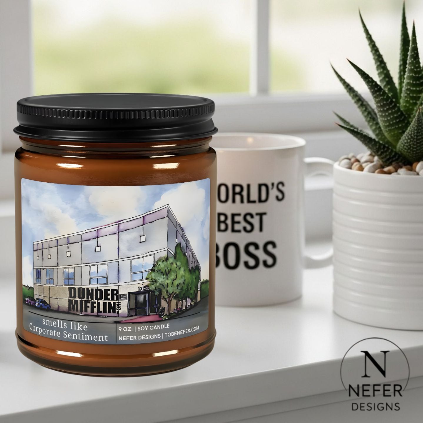 Candle jar with a labeled  showing the the office show paper building design next to a wolrd's best boss mug and plant on a surface