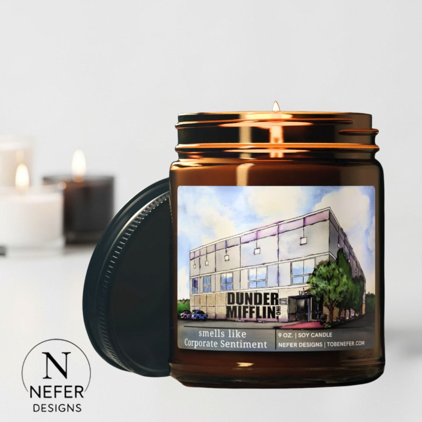 Candle in a jar with a building illustration and 'Dunder Mifflin' text, featuring the Nefer Designs logo.