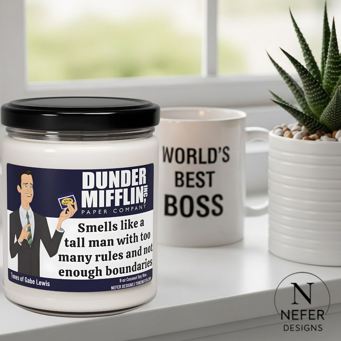 Scented soy candle and mug with 'Dunder Mifflin' branding on a surface with a plant in the background