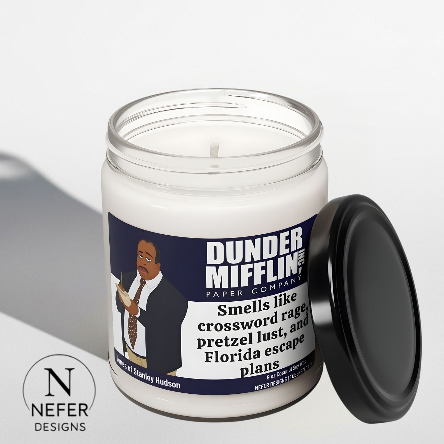 Candle in a jar with a label featuring 'Dunder Mifflin' branding on a light gray background.