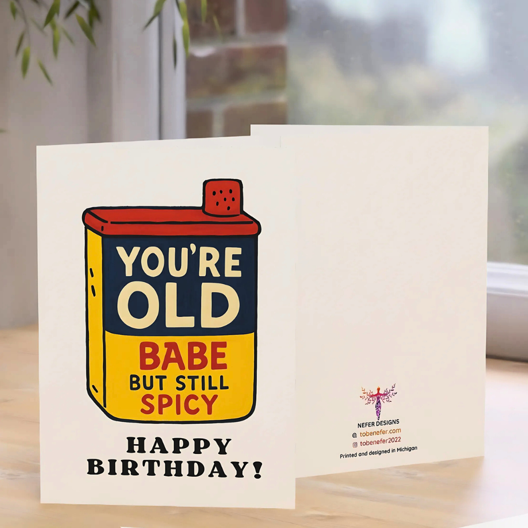 Birthday card with a humorous design of a spice container and text on a white background place on a wooden table.